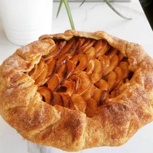 Whole apple galette on a white marble counter