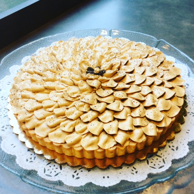 Chocolate tart decorated with espresso buttercream petals, on a glass plate.