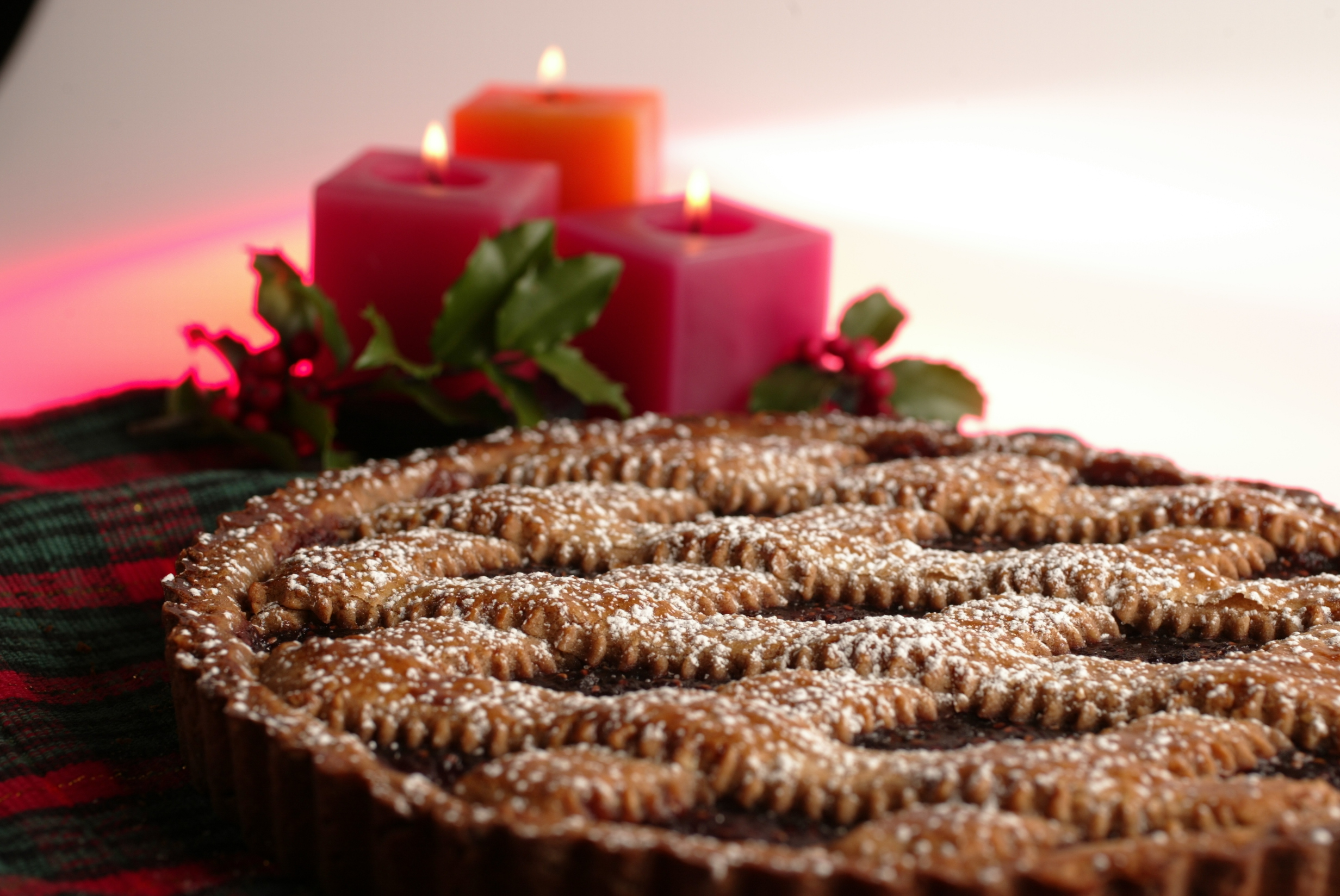 Raspberry Linzer torte with red candles and sprigs of holly