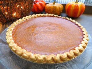 Pumpkin pie in front of small decorative pumpkins.