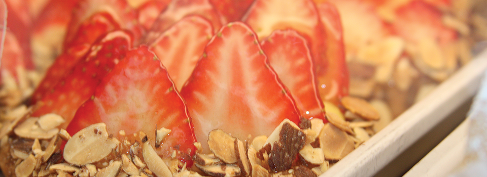 Close-up of strawberry custard tarts garnished with sliced almonds.