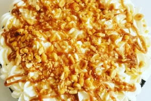Overhead view of whole pie covered with whipped cream, caramel, and peanuts