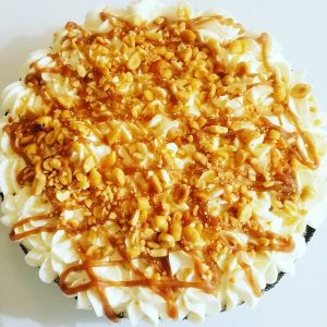 Overhead view of whole pie covered with whipped cream, caramel, and peanuts