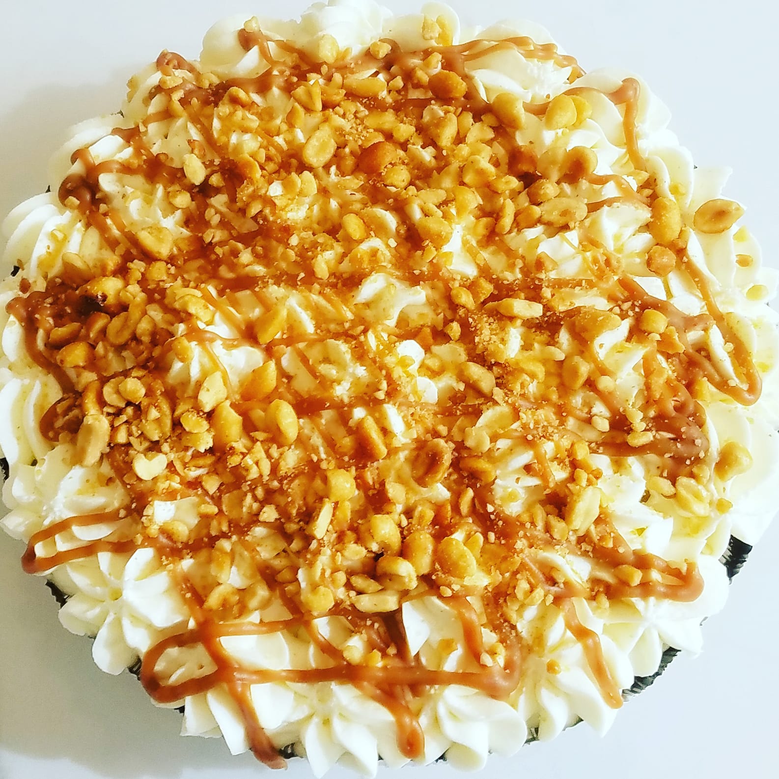 Overhead view of whole pie covered with whipped cream, caramel, and peanuts