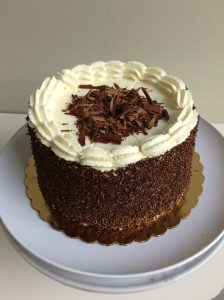 Whole chocolate mousse torte, frosted with whipped cream and decorated with chocolate sprinkles and chocolate shavings